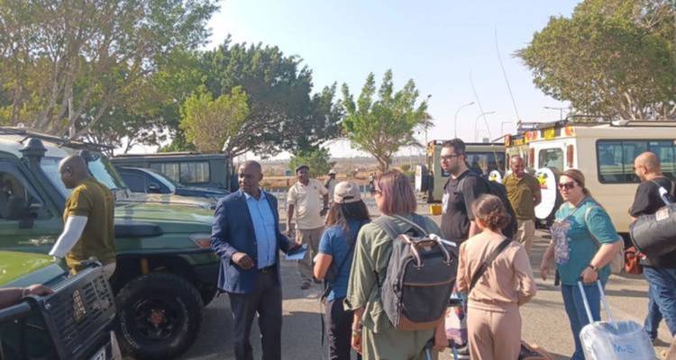 Groep mensen en safari voertuigen op parkeerplaats.