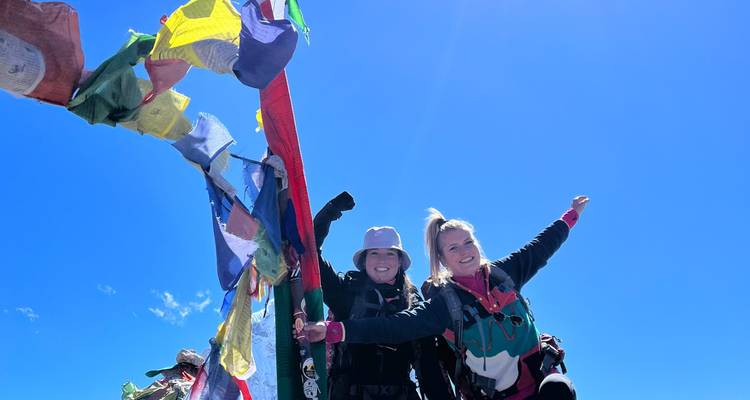 Wandelaars die feesten op een berg met gebedsvlaggen op de achtergrond.