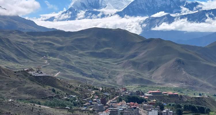 Un village et des montagnes lointaines sous un ciel clair.
