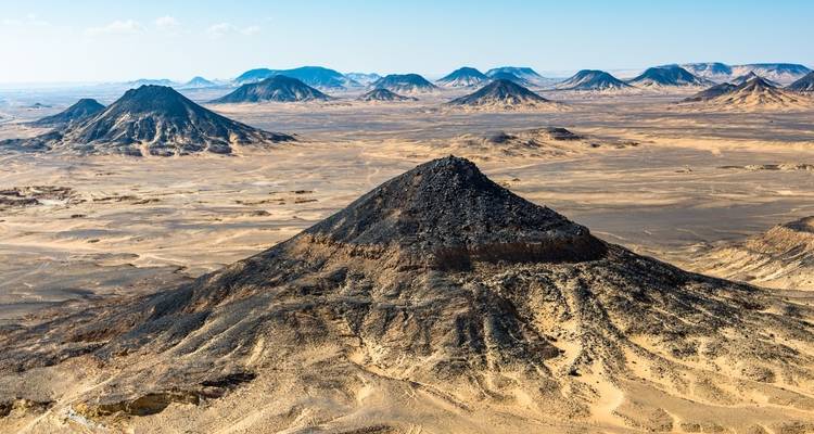Luftaufnahme einer Wüste mit Bergen und Dünen.