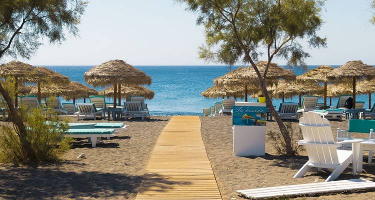 Strandszene mit Sonnenschirmen und dem Meer.