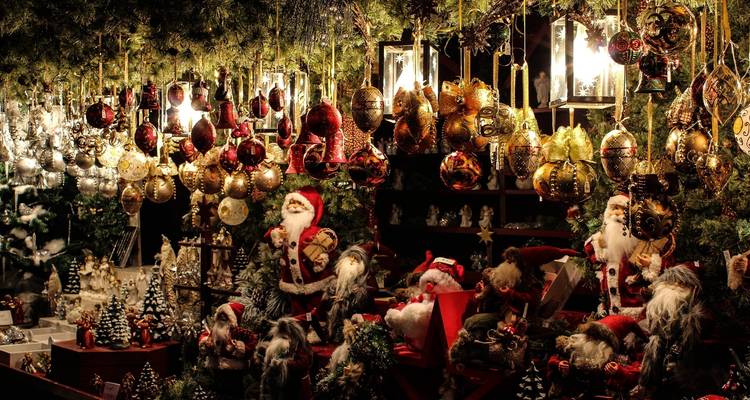 Puesto festivo desbordante de adornos navideños colgantes, esferas y figuras de Santa Claus.