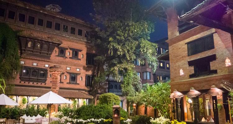 Traditional architectural buildings in a lush garden at night.