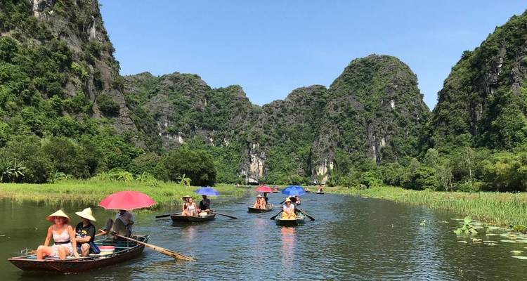Tourists on small boats in a river surrounded by lush greenery and mountains.