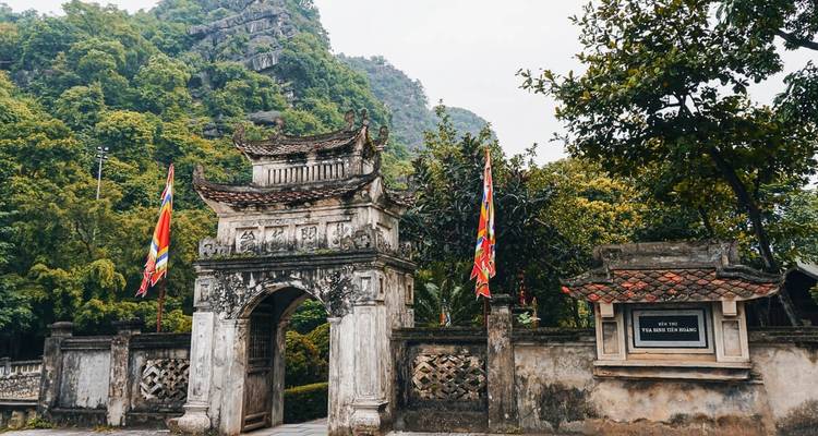 Een historische poort met traditionele architectuur tegen een bladrijke achtergrond.