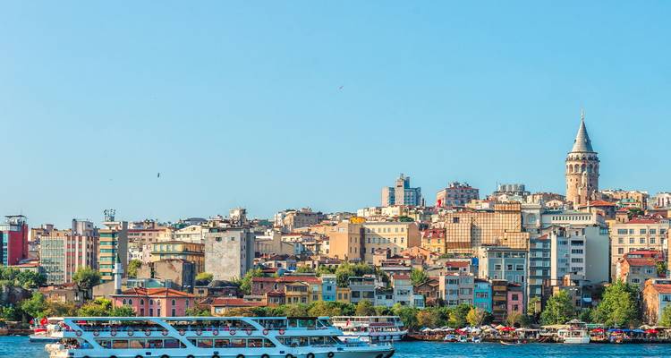 Colorful Istanbul waterfront with a passenger ferry on the Bosphorus and Galata Tower rising above.