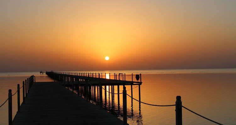 Une jetée sereine s'étendant dans un océan calme au lever du soleil.