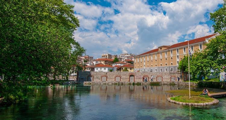 Rustige vijver met gebouwen en bomen eromheen.