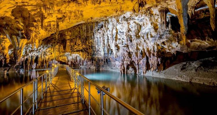 Binnenaanzicht van een grot met een loopbrug over water.
