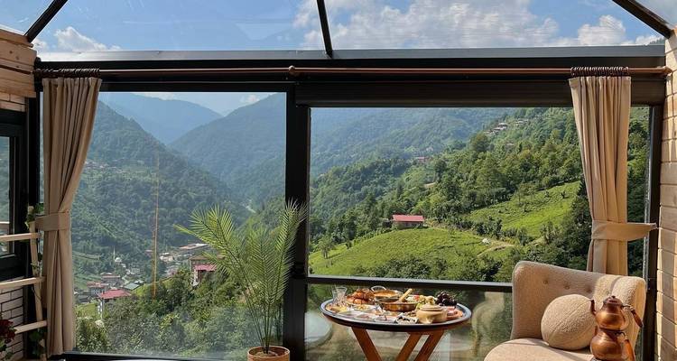 Panoramisch uitzicht op een vallei met groen en een gedekte ontbijttafel.