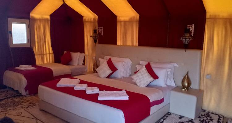 Interior de una tienda de campaña con múltiples camas elegantemente dispuestas.