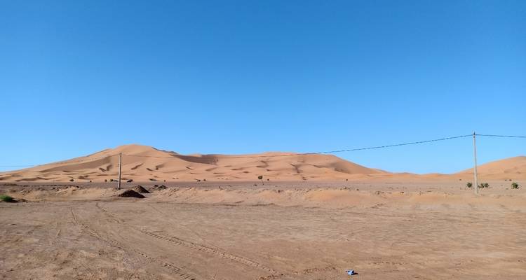 Vista lejana de dunas de arena bajo un cielo azul despejado.
