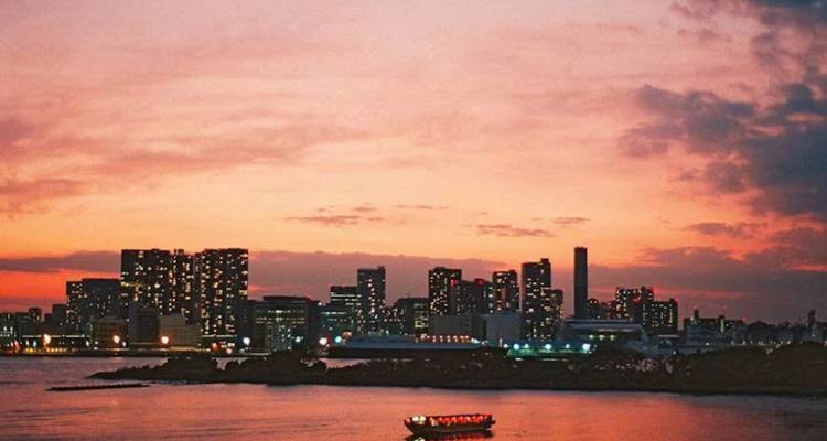 Horizon urbain au coucher du soleil avec un bateau au premier plan.