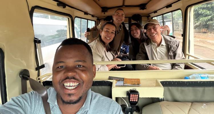 Selfie of cheerful guide and travellers inside a safari van en route to the park.