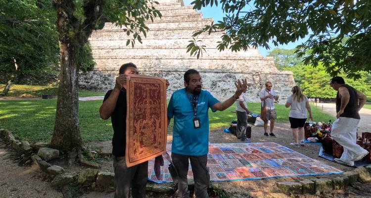 Un vendeur local expose des tapis tissés destinés aux touristes près d'une pyramide maya.