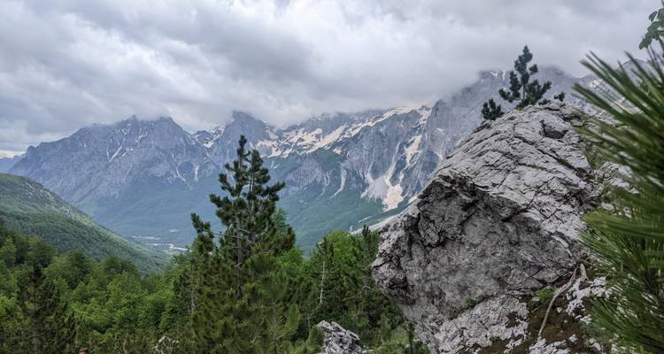 Pics rocheux avec forêt verte et ciel nuageux.