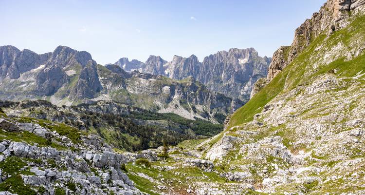 Pics de montagne déchiquetés avec des pentes vertes.