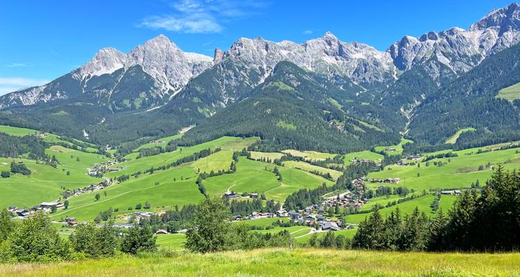 Ein Panoramablick auf ein bergiges Tal mit Dörfern und Feldern.