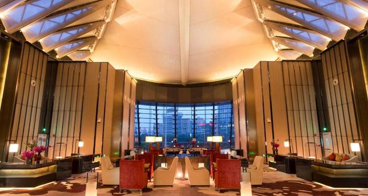 Spacious hotel lobby with grand architectural design and large windows.