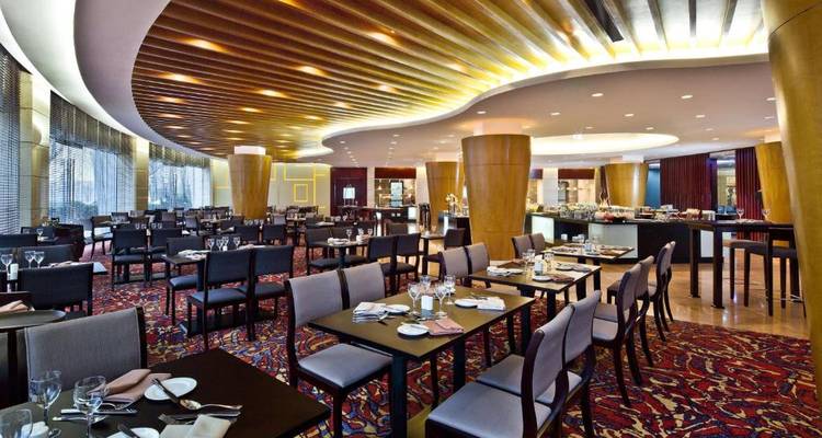 Modern restaurant interior with stylish tables and elaborate ceiling decor.