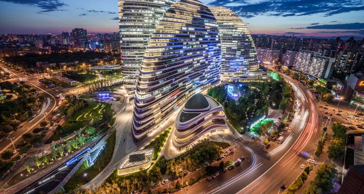 Vista nocturna de las torres curvas iluminadas del Wangjing SOHO entre las luces de la ciudad