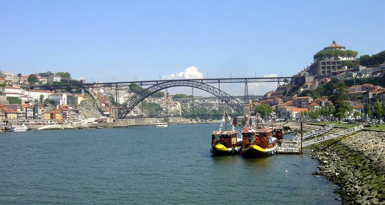 Historische brug over een rivier met afgemeerde boten.