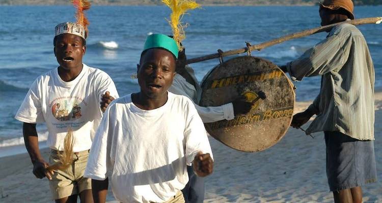 Musicians performing on the beach by water.