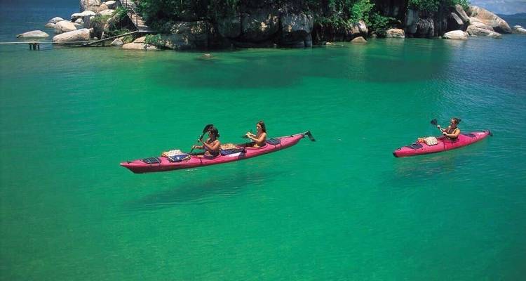 People kayaking in clear water surrounded by rocks.