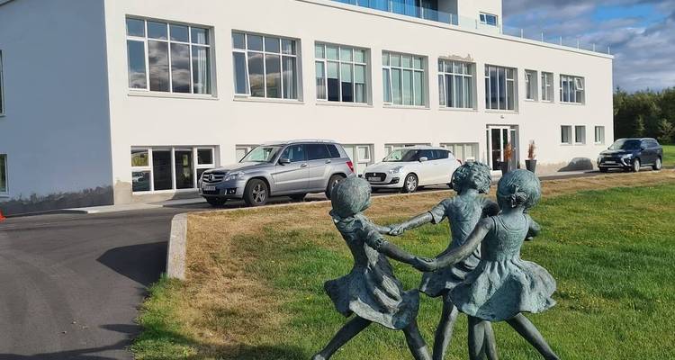 Statue von tanzenden Kindern vor einem modernen Gebäude.