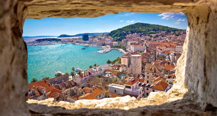 Un paysage urbain avec une vue sur le bord de mer encadrée par d'anciens murs de pierre.