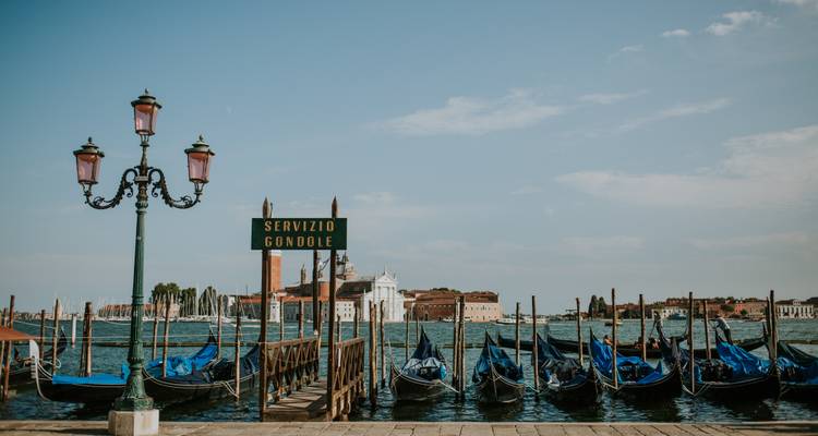 Góndolas alineadas con vista a través de un canal veneciano.