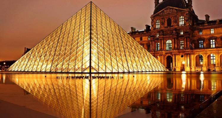 Illuminated glass pyramid at the Louvre at dusk.