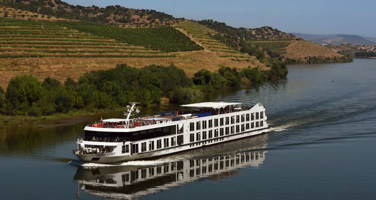 Ein Kreuzfahrtschiff, das auf einem Fluss fährt, mit terrassenförmigen Weinbergen an den Hängen.