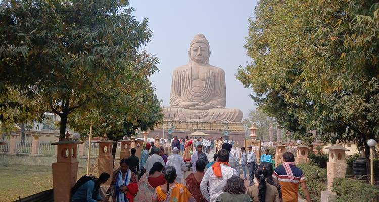 Large Buddha statue with visitors in a garden.