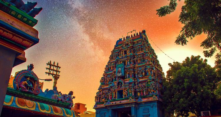 Ein Tempelturm mit detaillierten Skulpturen vor einem Sternenhimmel.