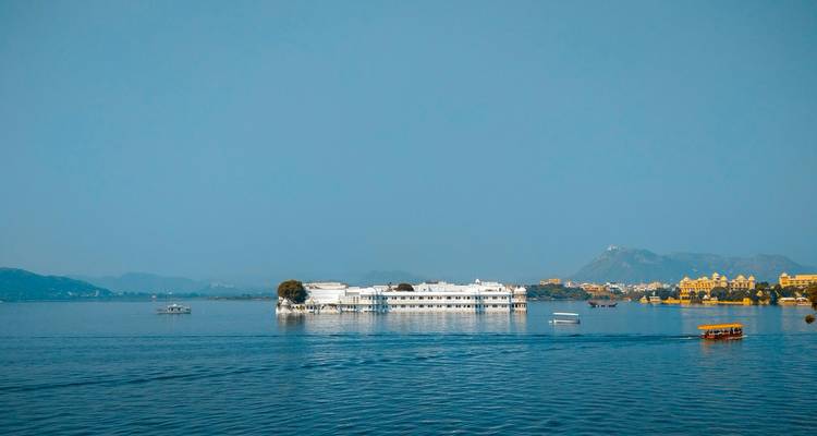 Floating palace in the middle of a lake with mountains in the background.