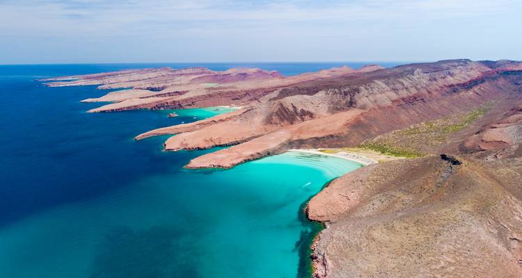 Aerial panorama of red desert coastline and brilliant turquoise bays near La Paz, Baja California Sur.