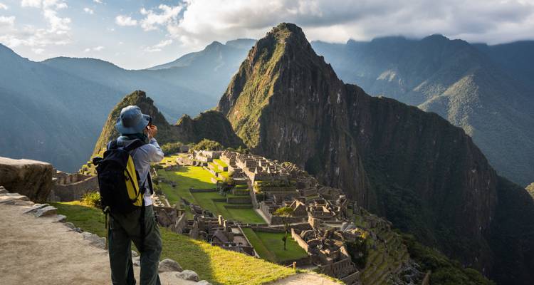 Solo trekkingliefhebber die de iconische ruïnes van Machu Picchu fotografeert met steile groene bergen op de achtergrond.