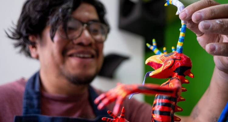 Une personne tenant une figurine d'alebrije colorée.