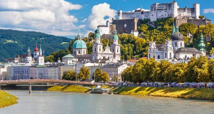 Large fortress on a hill overlooking a river in a scenic city.