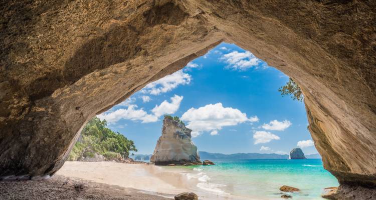 Vue depuis l'intérieur d'une grotte vers la mer et les falaises rocheuses.