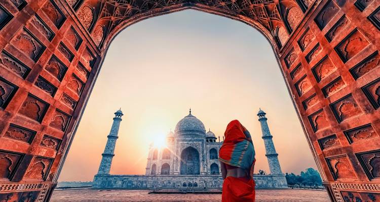 Silhouet van een persoon gehuld in traditionele kleding met het gezicht naar de Taj Mahal.