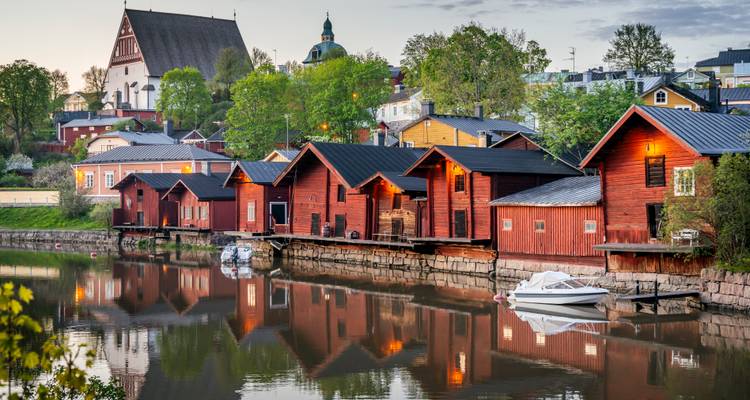 Les emblématiques entrepôts rouges au bord de la rivière et les flèches d'église reflétées dans les eaux calmes de Porvoo, en Finlande