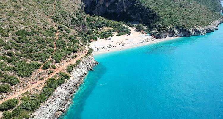 Aerial view of a secluded beach with blue ocean and greenery.