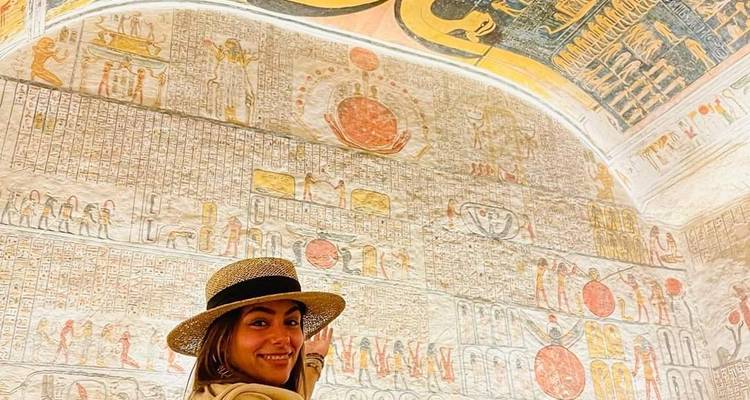 Eine Person, die vor einer Wand mit ägyptischen Hieroglyphen lächelt.