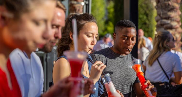 Los viajeros disfrutan de bebidas congeladas coloridas al aire libre en un día soleado.