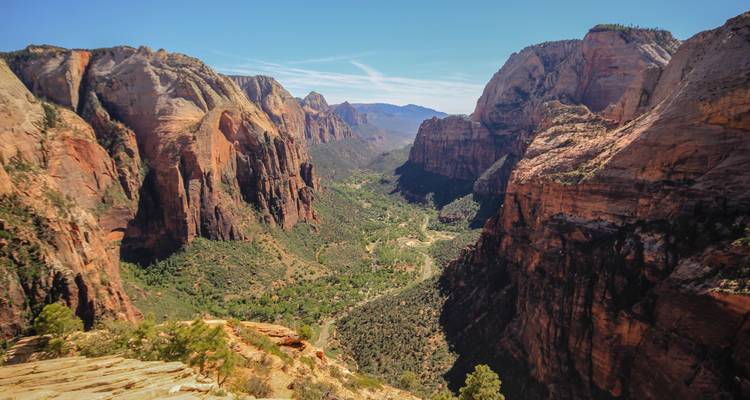Spectaculair canyonuitzicht met verticale zandsteenwanden rond een groen dal