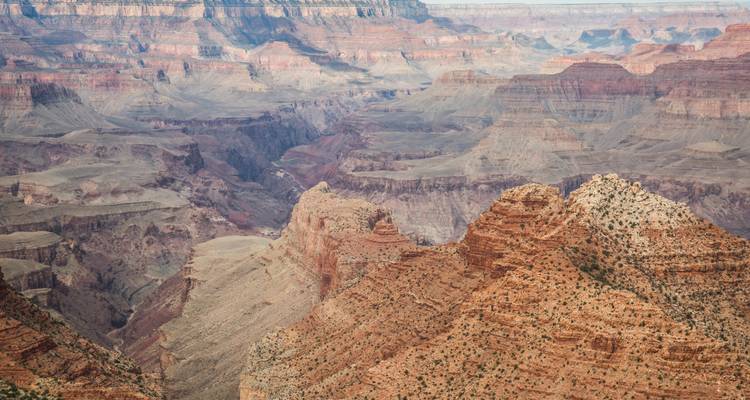 Les formations rocheuses en couches de couleurs variées s'étendent sur un vaste paysage de canyon
