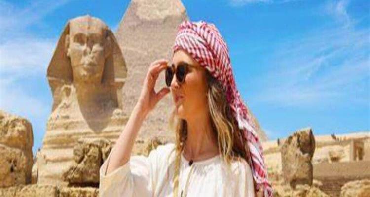 Jeune femme portant un foulard qui pose avec le Sphinx et la pyramide en arrière-plan par une journée ensoleillée