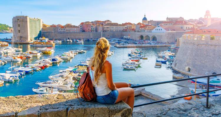 Eine Frau mit einem Rucksack mit Blick auf den Hafen von Dubrovnik.